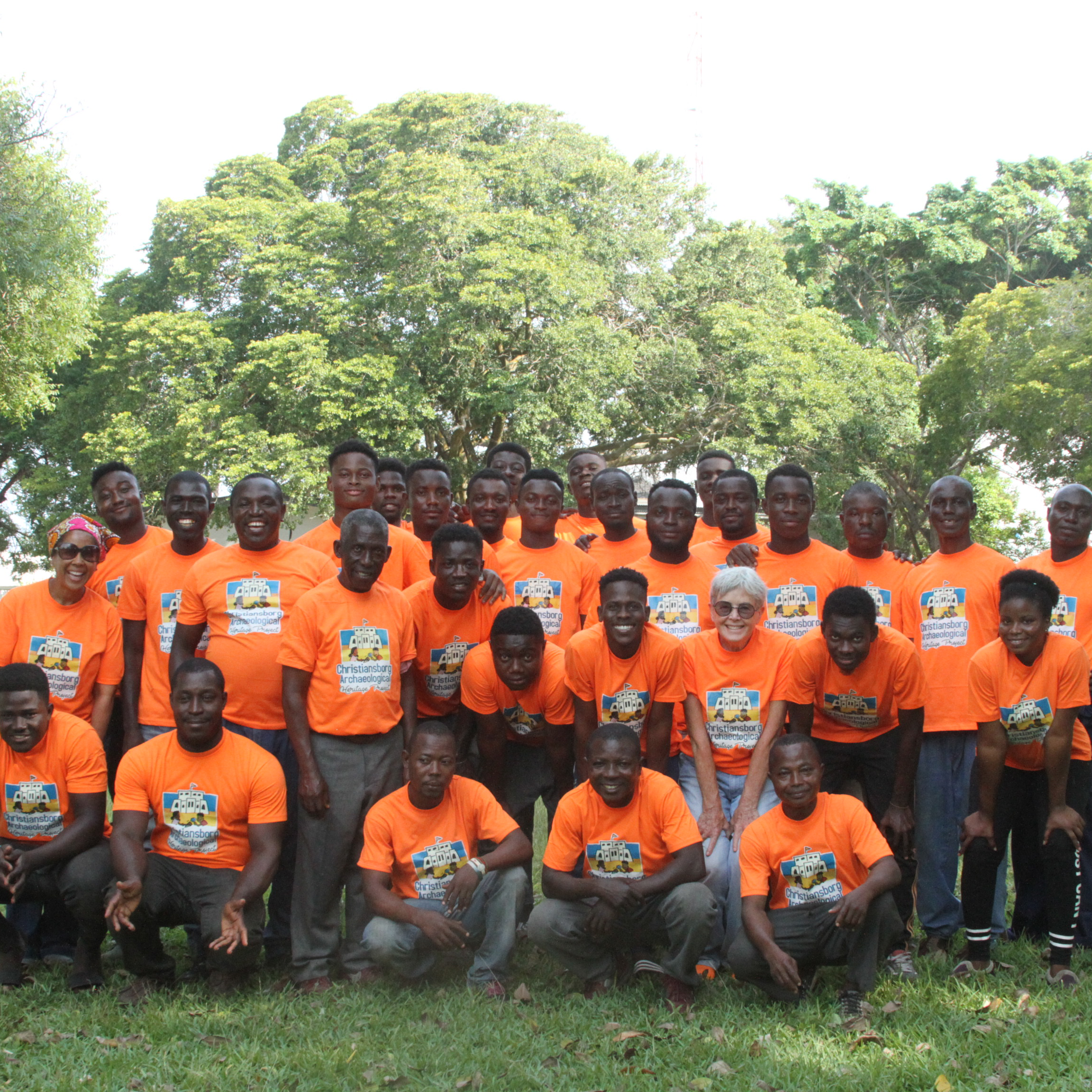 A large group of people all wearing orange shirts and lined up for the camera